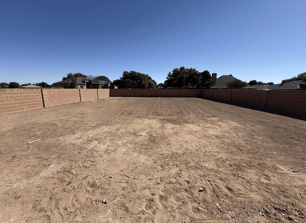 A bare yard space ready for landscaping with various plants.