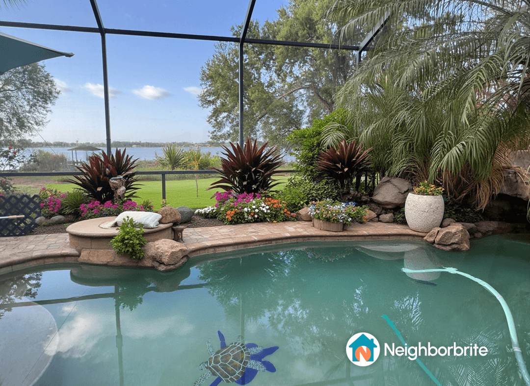 A view of a pool area with plants and flowers, showing the left side hardscape to be removed.