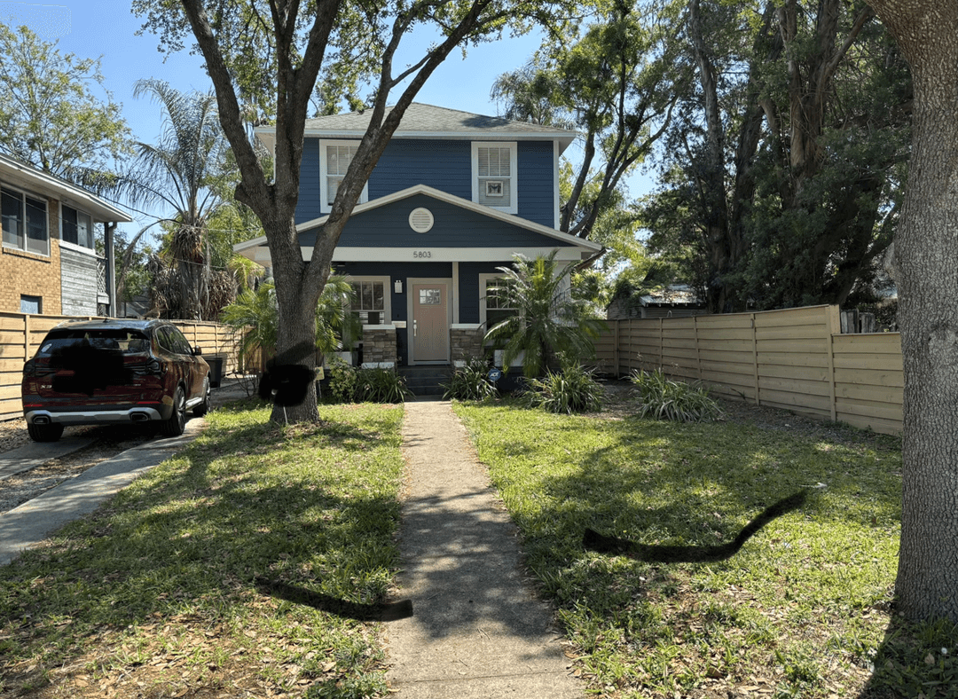 Front yard with two large oak trees and a driveway in Central Florida.