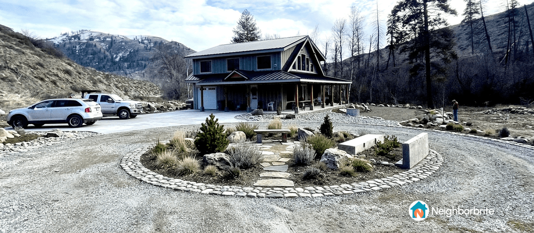A circle driveway with a landscaped island and vehicles parked.