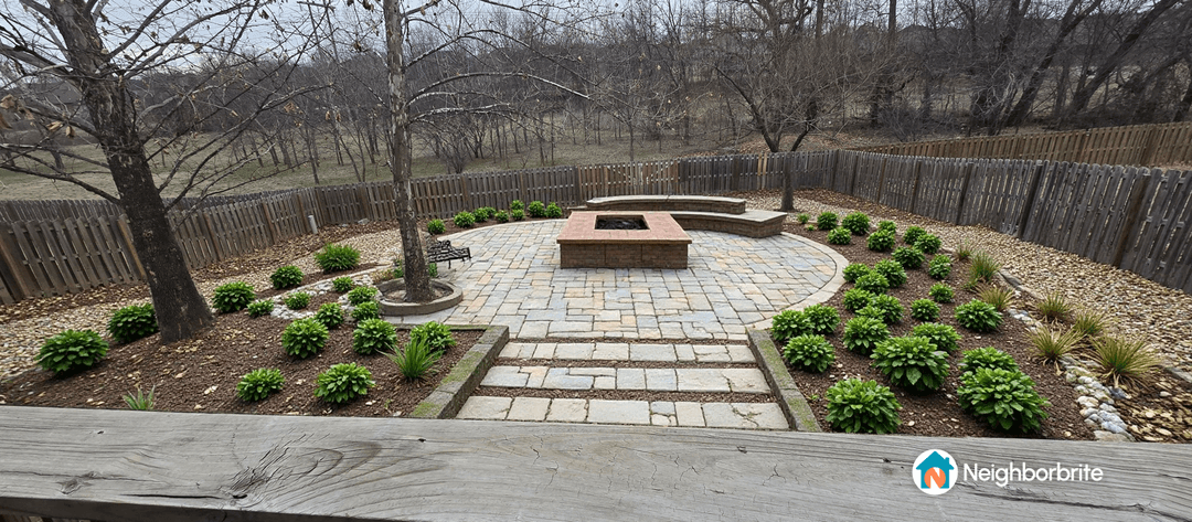 A well-designed backyard with a stone patio and fire pit.