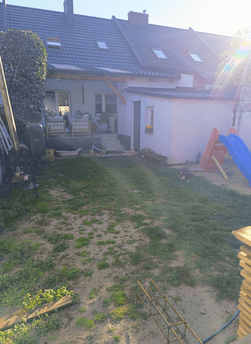 A backyard with grass, a slide, and a small building, seeking garden design ideas.