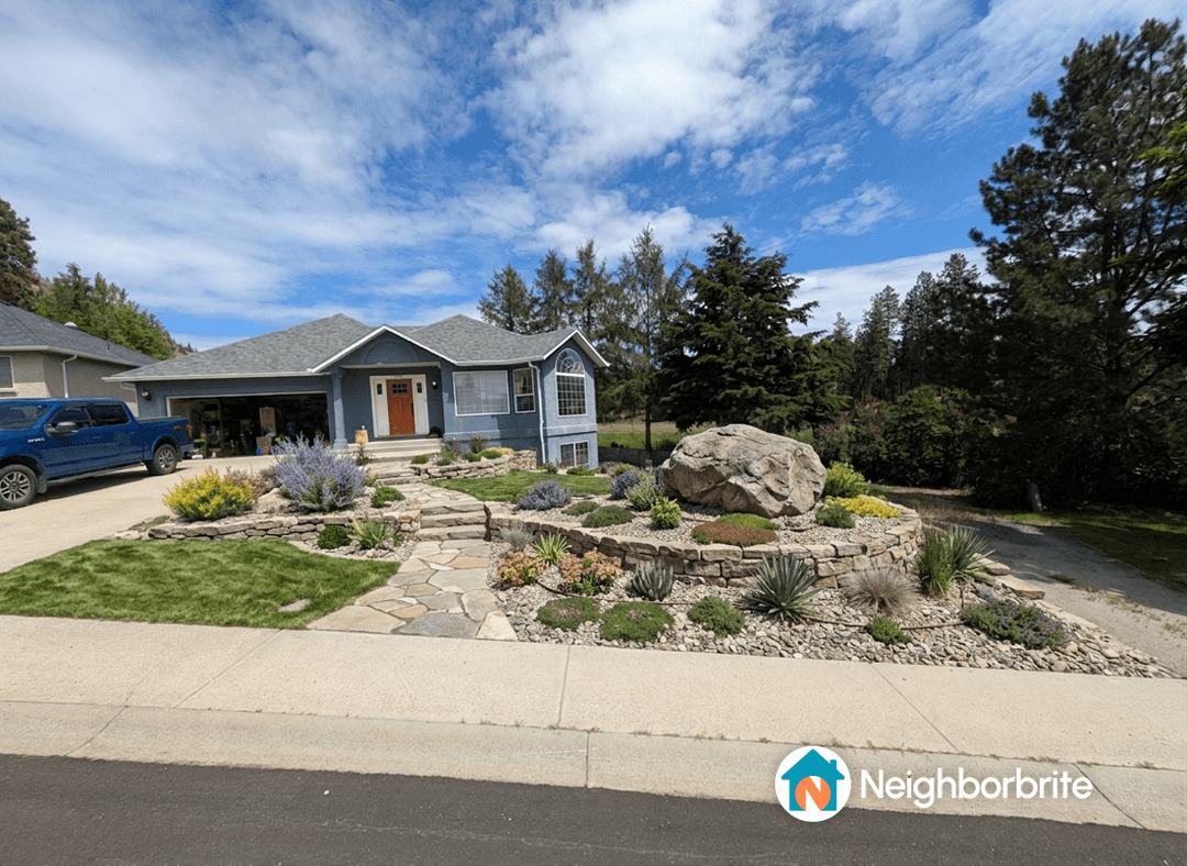 A landscaped yard featuring drought-resistant plants and a large rock.