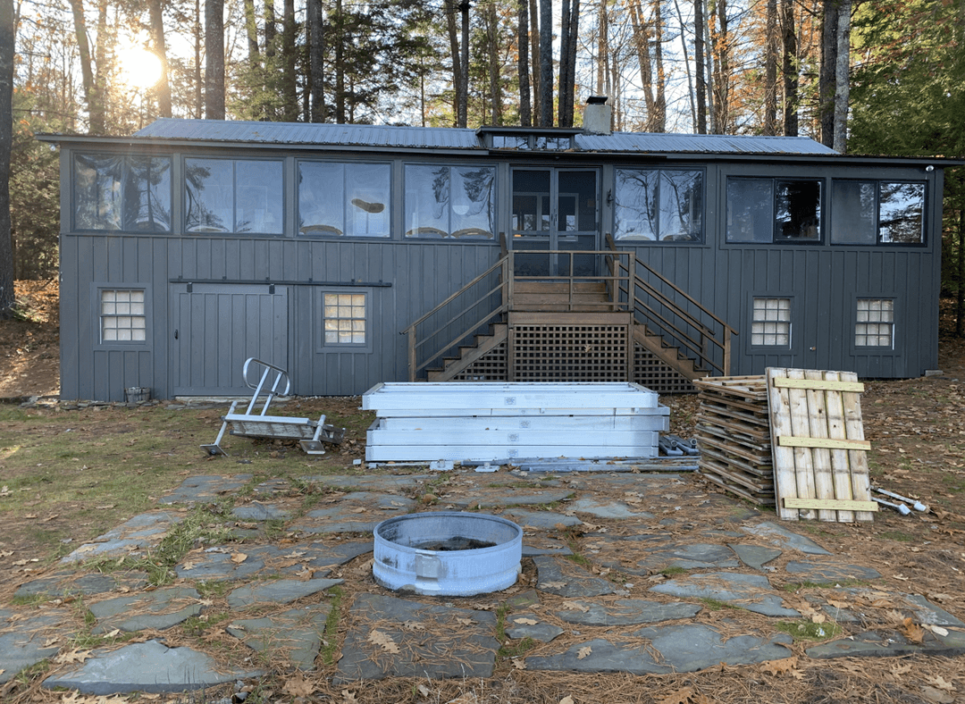 A Maine lakeside cottage with a gray exterior and wooden stairs.
