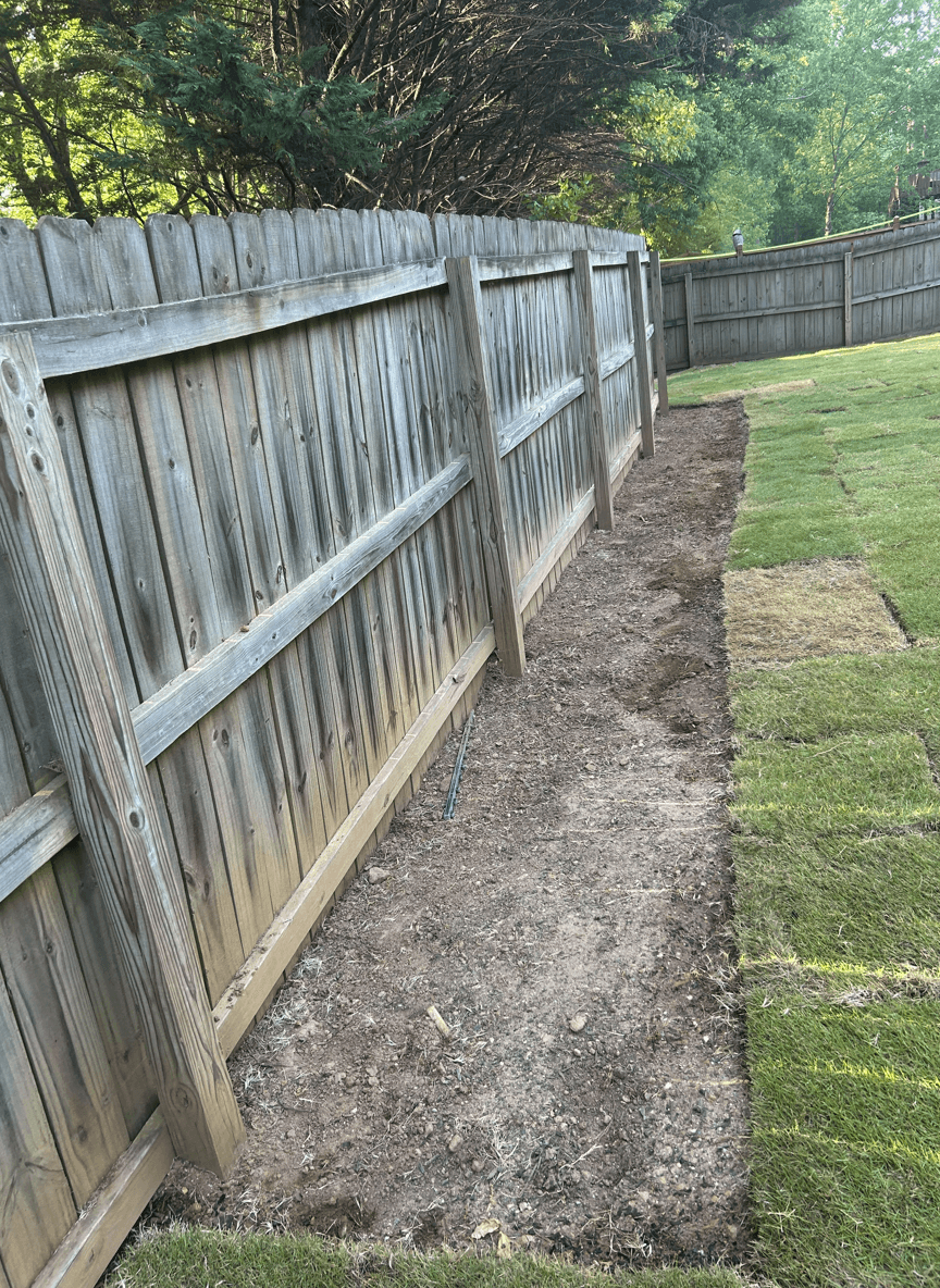 A yard space along a wooden fence, ready for planting perennials.