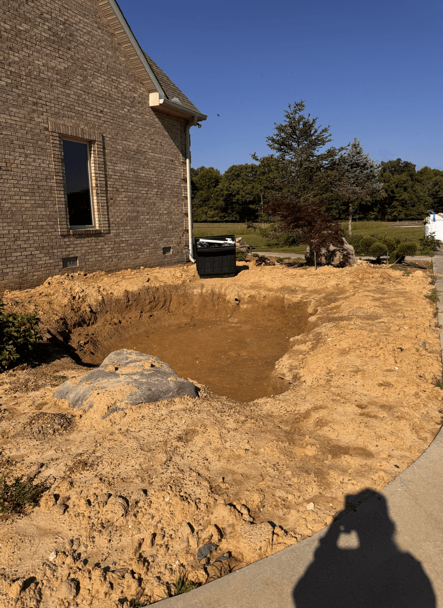 Excavated area for a natural waterfall design in a yard.