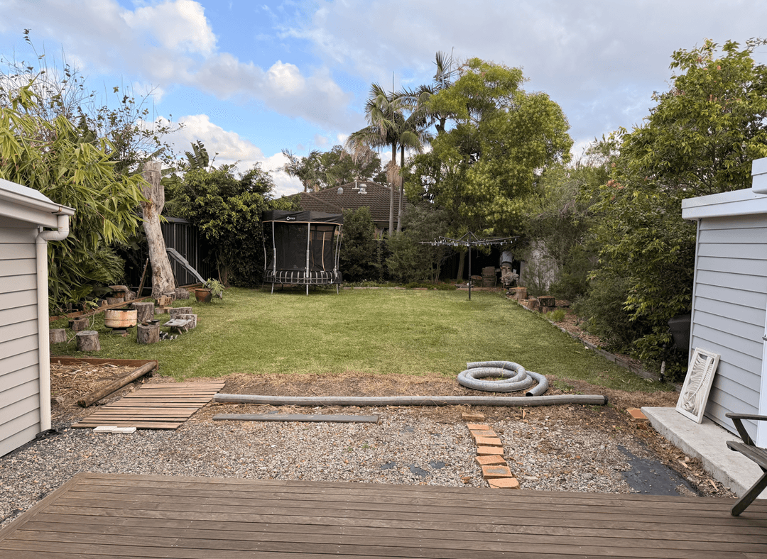 View of a backyard space off a deck with grass and trees.