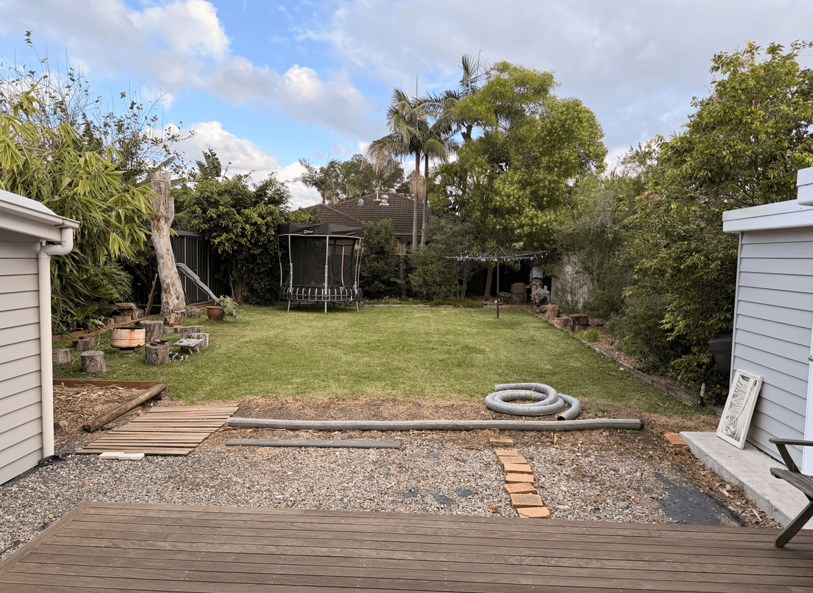 View of a backyard space off a deck with grass and trees.