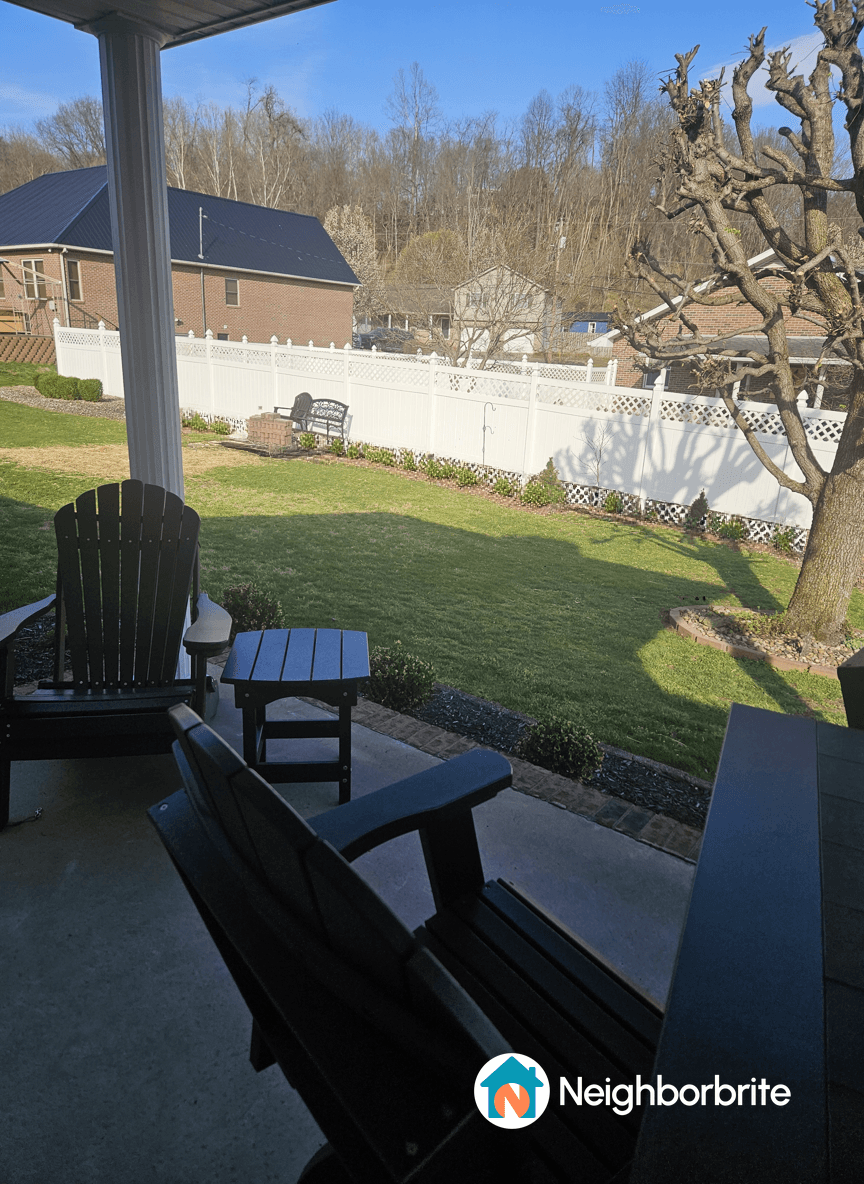 View of a minimalist yard with fenceline plants and seating.