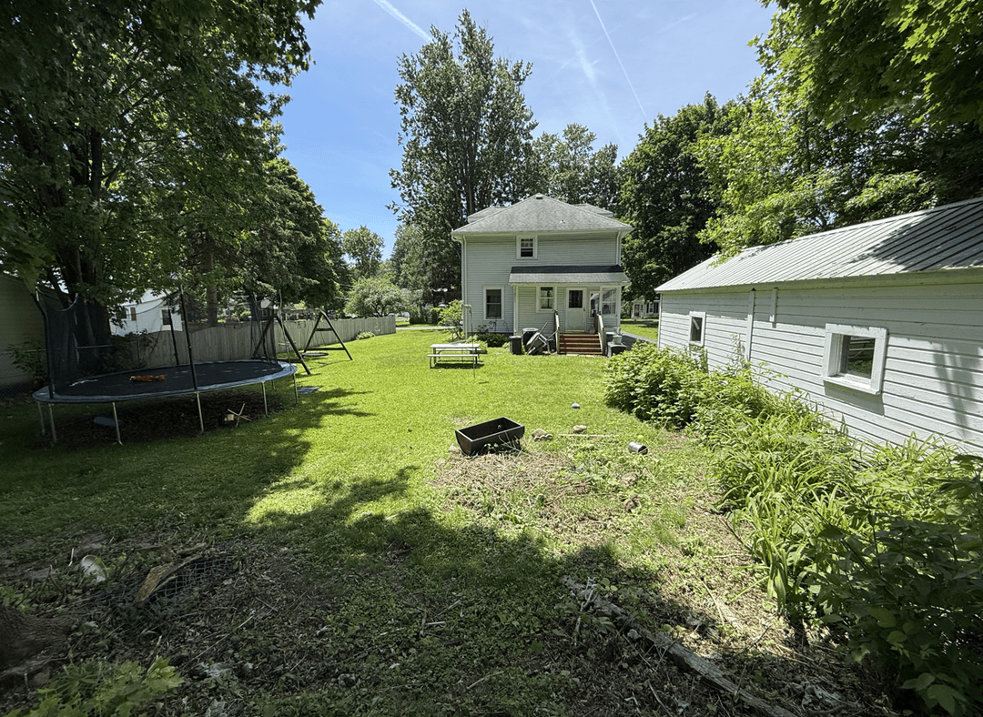Spacious backyard with trampoline, play area, and greenery.