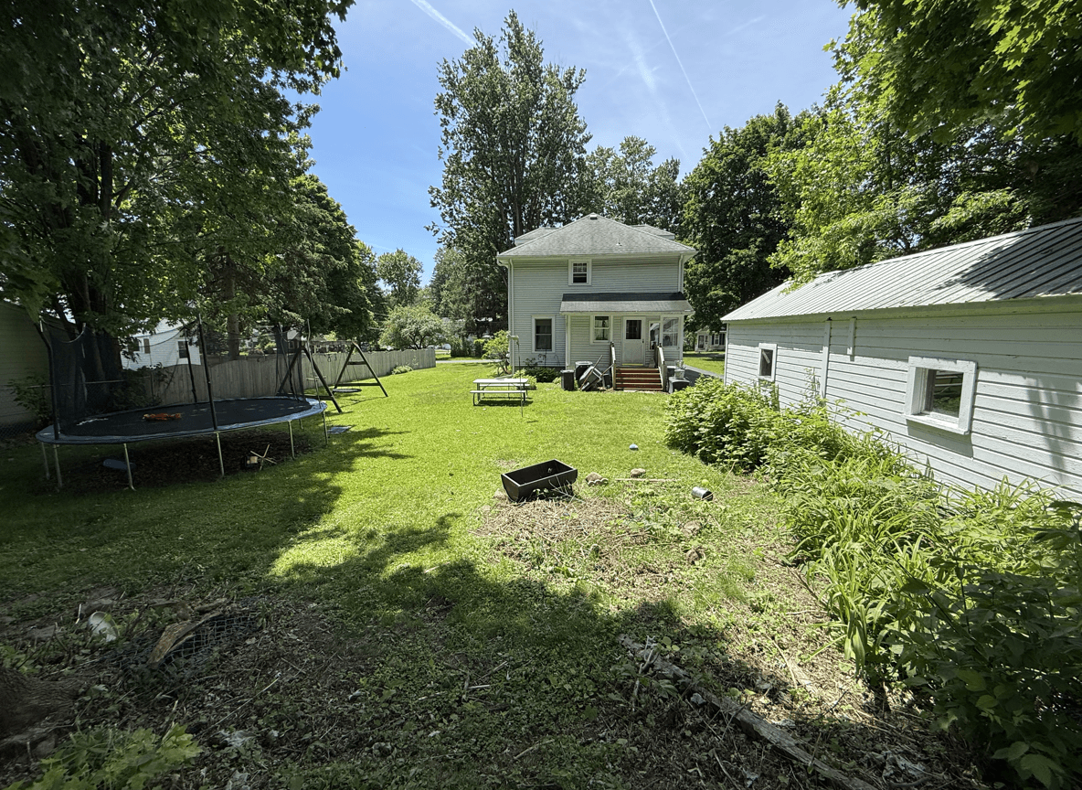 Spacious backyard with trampoline, play area, and greenery.
