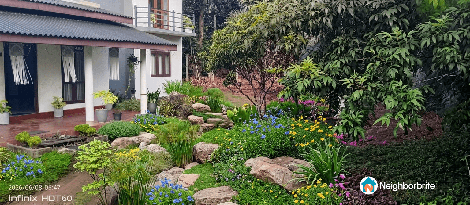 A vibrant garden with colorful flowers and rocks near a house.