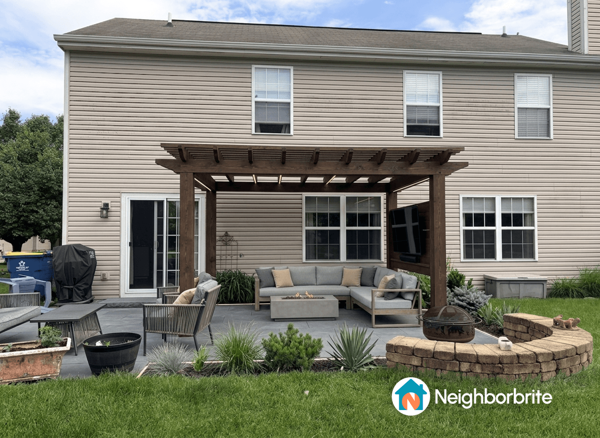 A backyard featuring a strong steel awning supported by poles, with a cozy seating area.