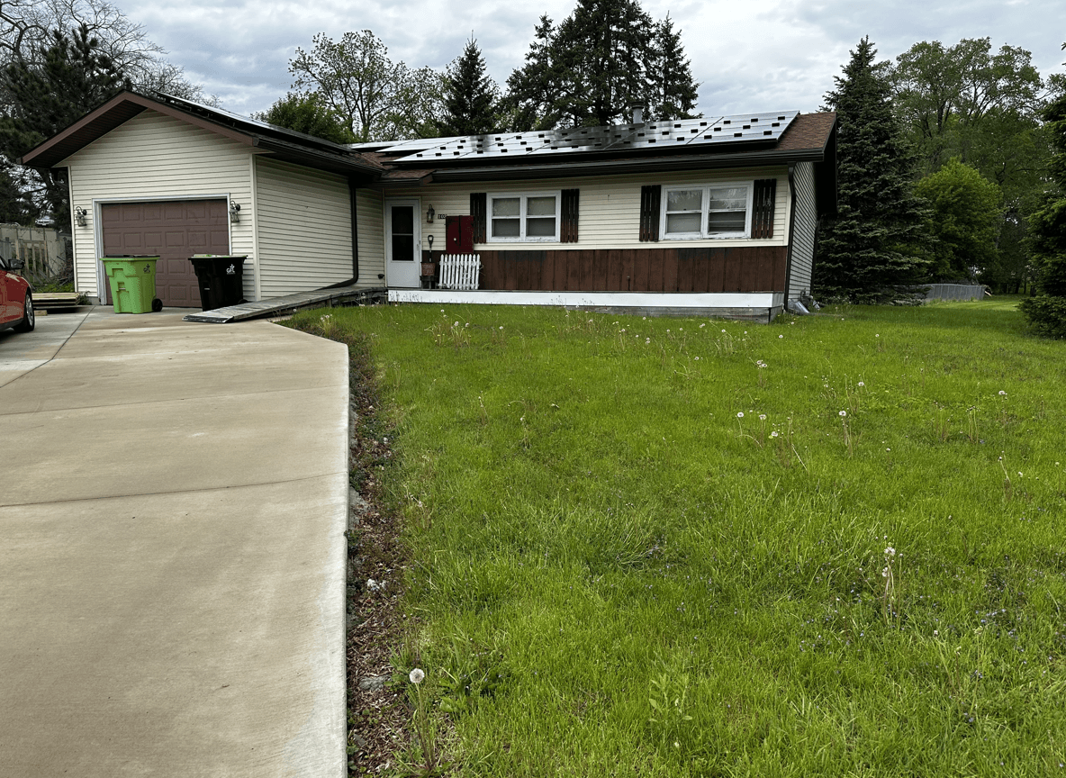 Front yard featuring a native plant landscape with green grass.