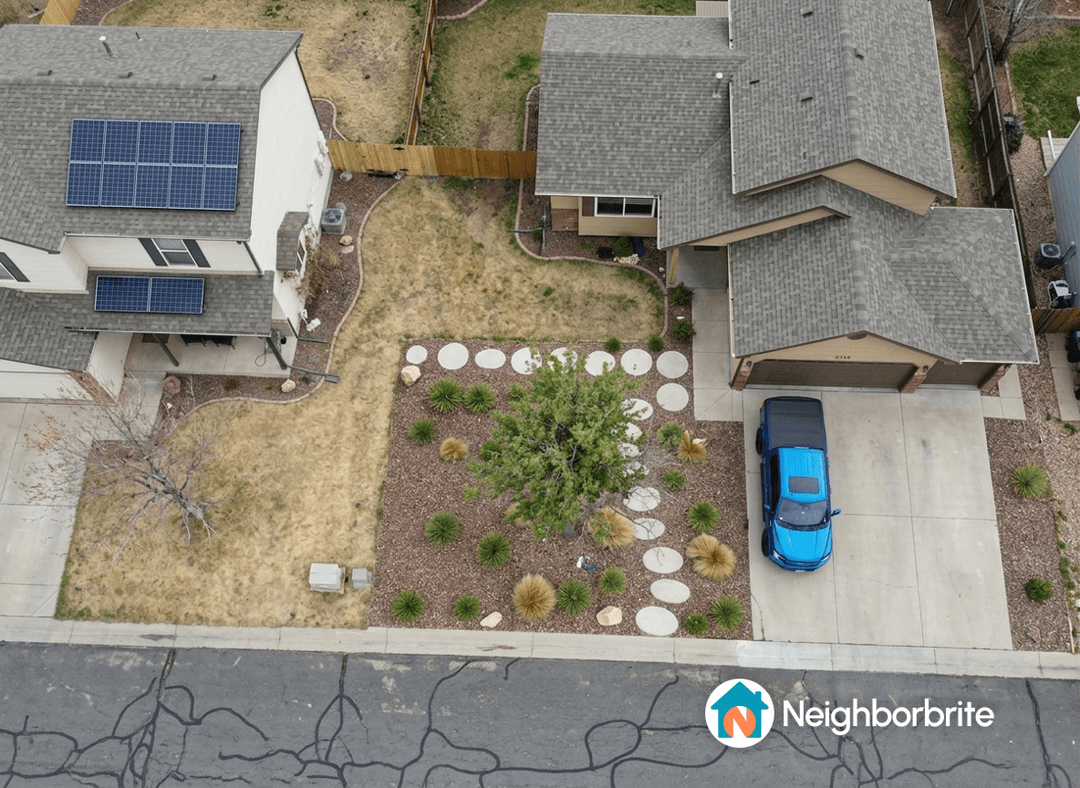 Aerial view of a yard with landscaping and a blue car.