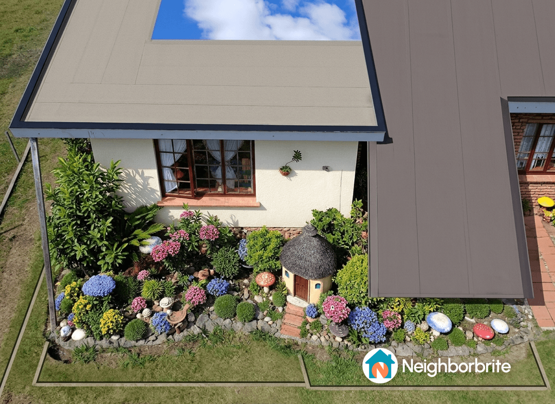 Aerial view of a house with a paving apron and vibrant flower garden.
