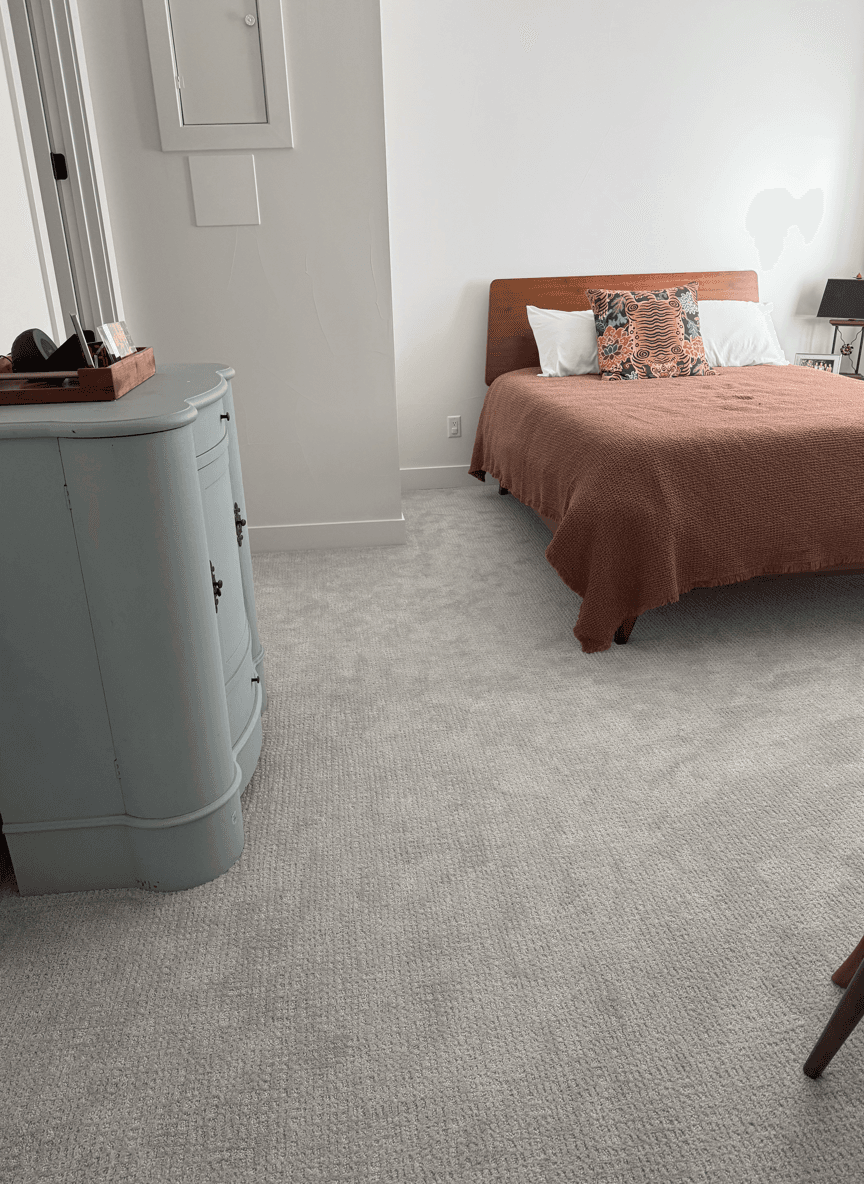 A light blue cabinet in a bedroom with a brown bedspread and colorful pillows.