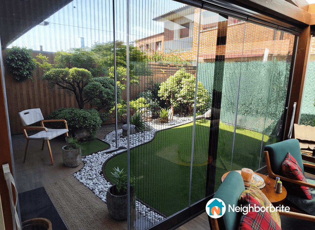 Vista de un patio con plantas, césped y muebles acogedores.