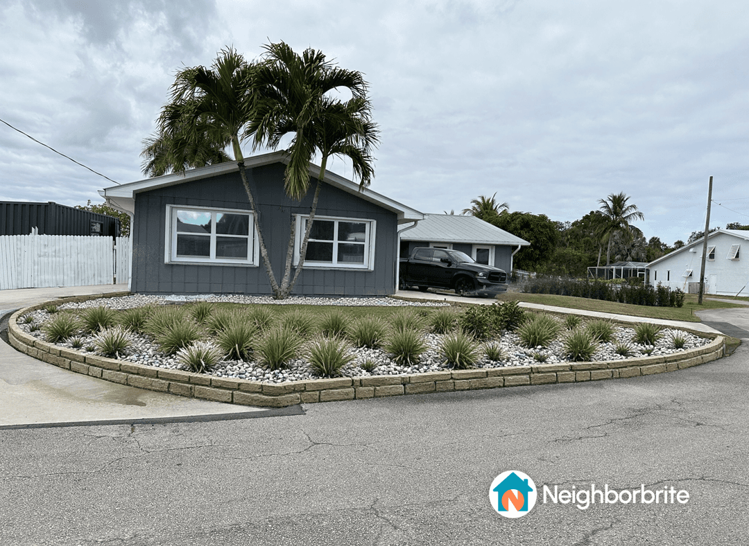 A beautifully landscaped yard with palm trees and decorative stones.
