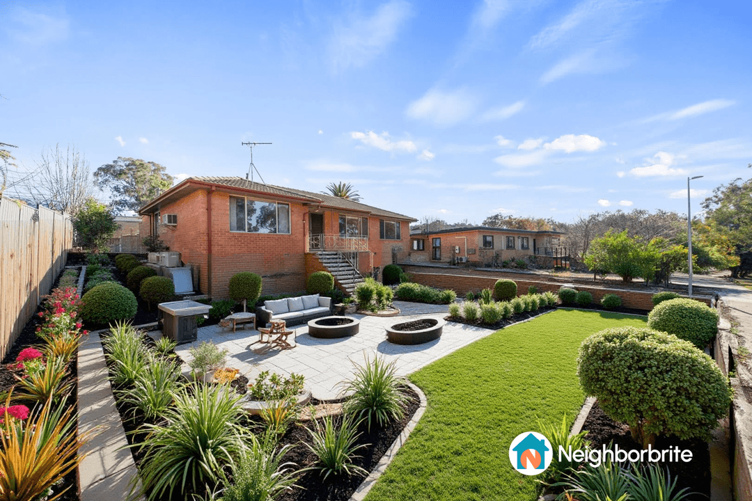 A beautifully landscaped yard featuring plants, seating, and fire pits.