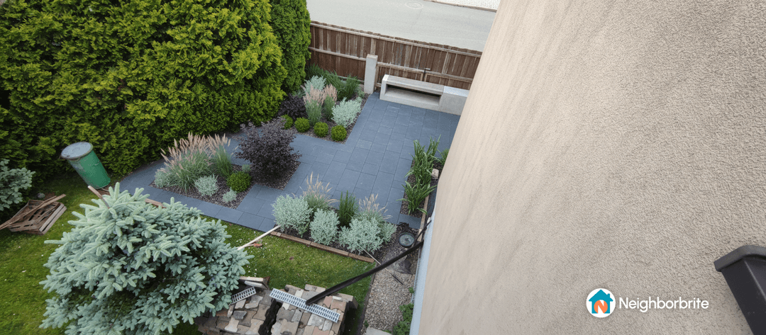 Overview of a yard with plants and paving, showing space for a garage entrance.