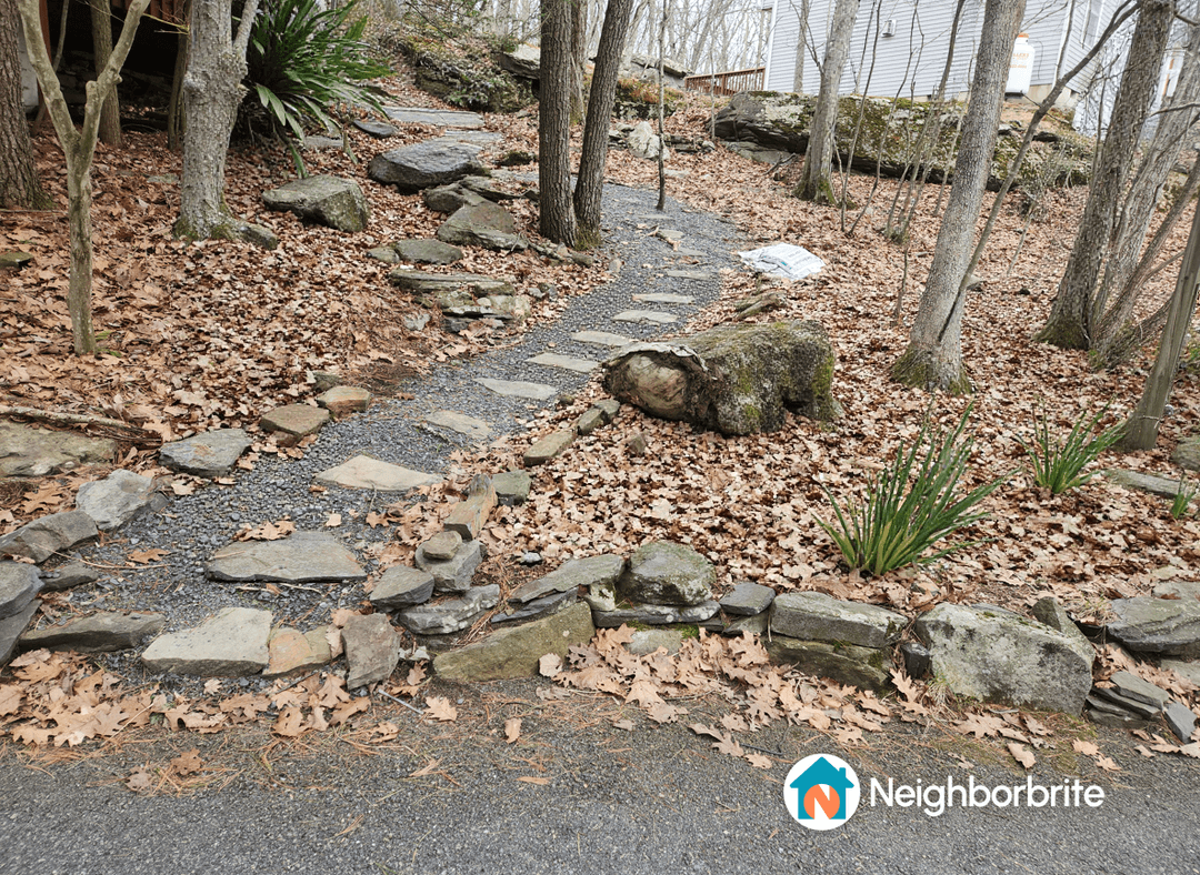 Rocky, sloped yard with a stone path and fallen leaves.