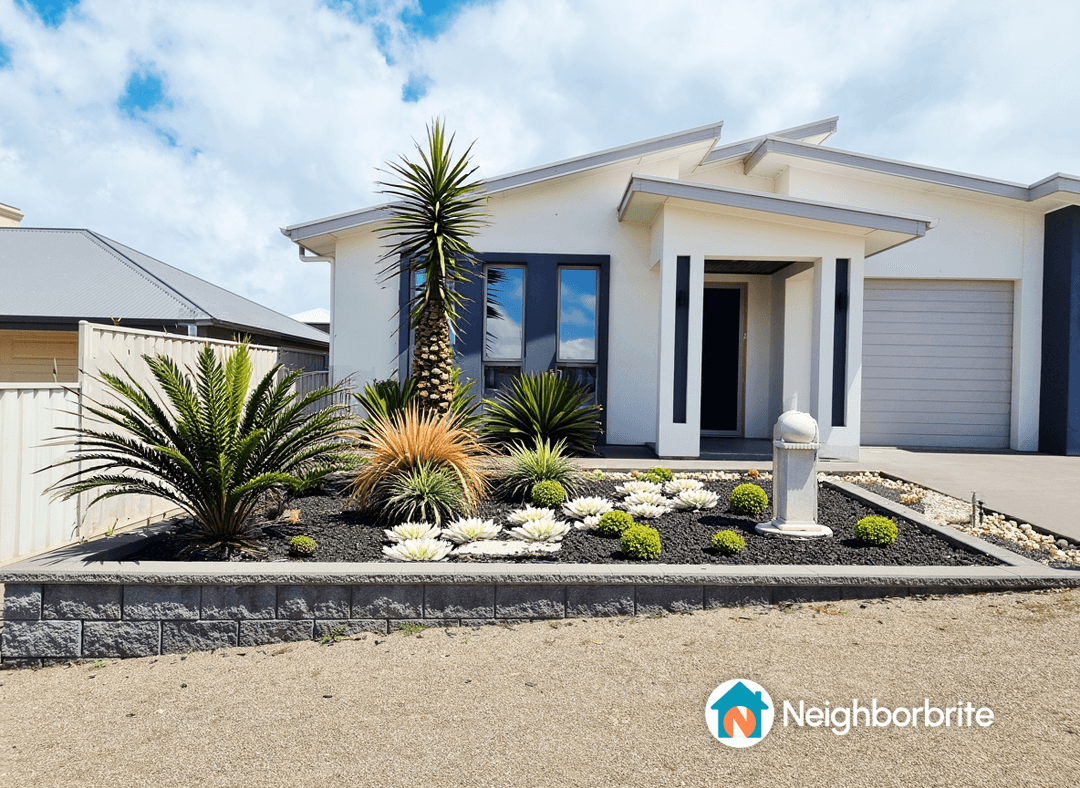 A modern home with landscaped garden featuring various plants and decorative stones.