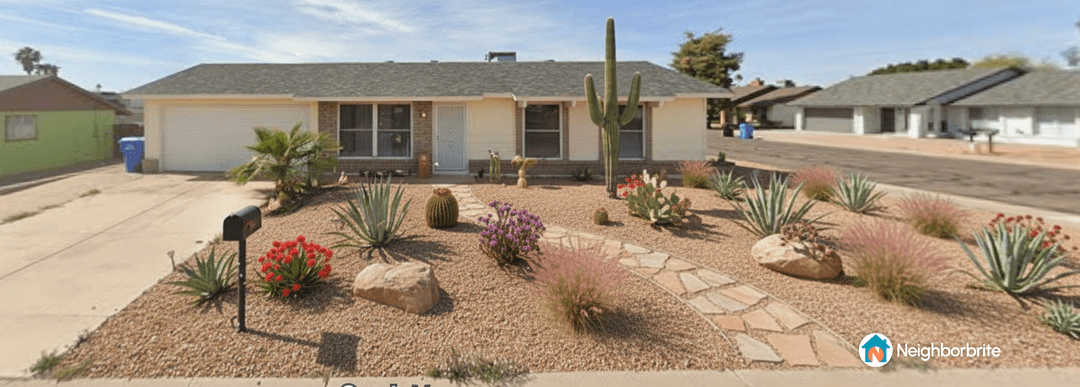Front yard with desert landscaping, featuring cacti and colorful plants.