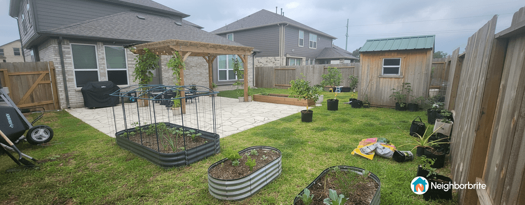 A backyard garden with raised beds, a pergola, and various plants.